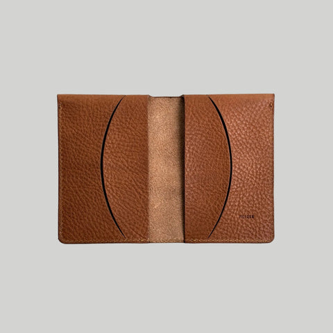 Brown leather cardholder with visible brand name on a light gray background