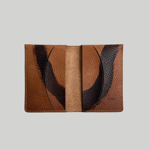 Brown leather cardholder with abstract design on a light gray background