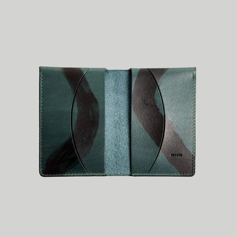 Green leather wallet with abstract design on a light gray background